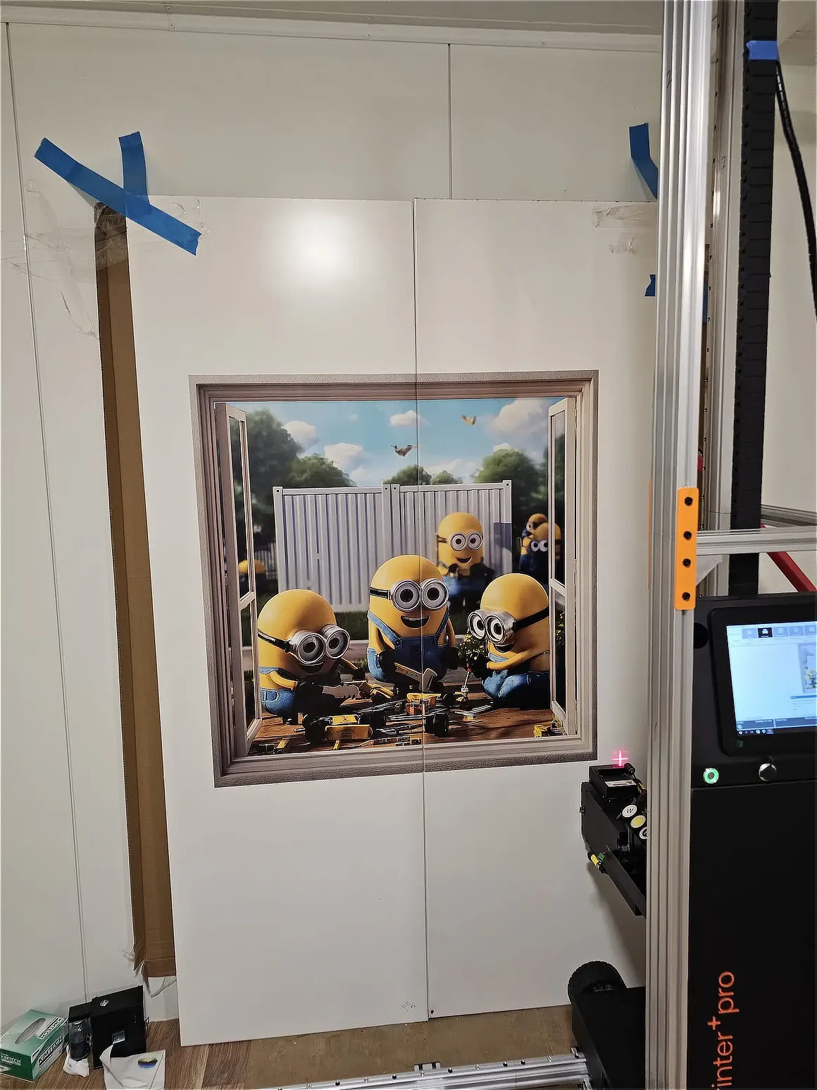 Dekoracyjny wydruk z Minionkami w ozdobnej ramie na ścianie